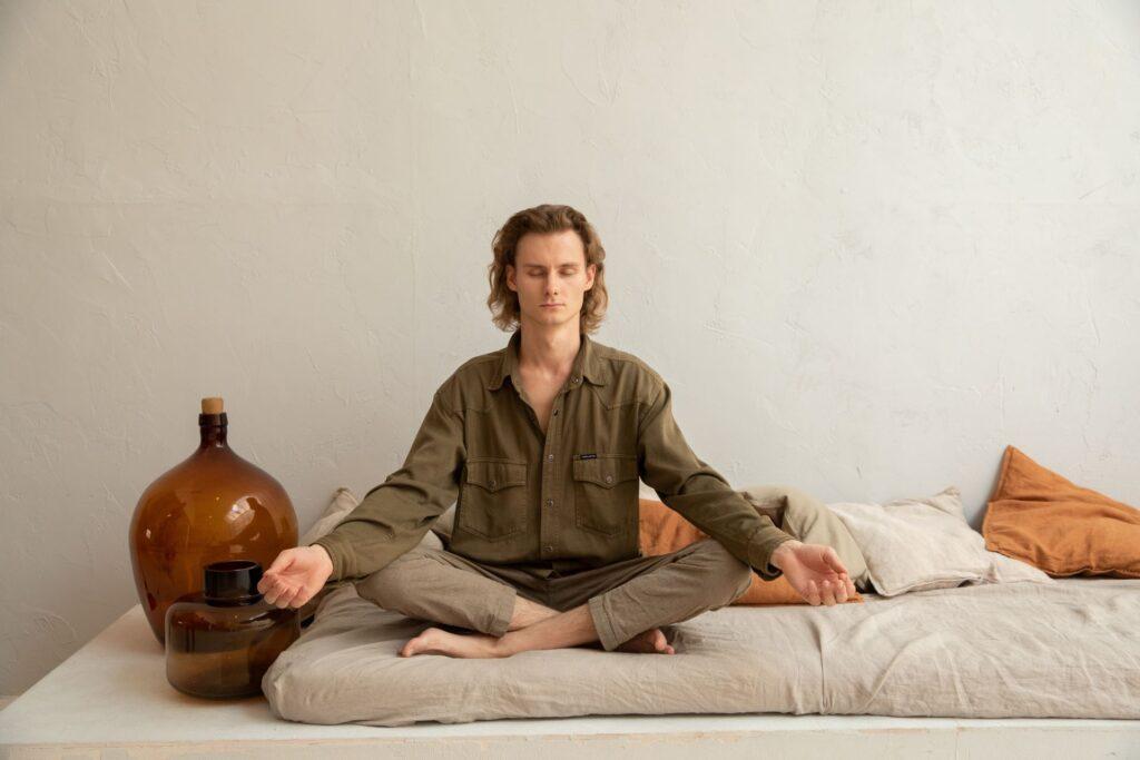 Eine Person meditiert auf einem Bett