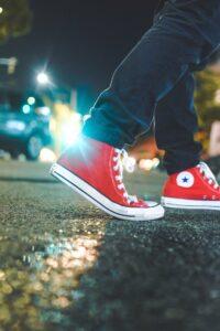 Blick aus der Froschperspektive auf eine Person, die ein Paar rote Converse All-Star-Sneakers trägt.