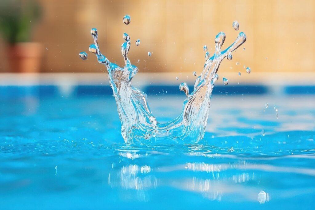 Detailaufnahme eines Wasserspritzers in einem Pool – Symbolbild fuer Sommer und Wasserqualitaet