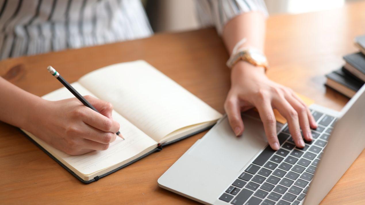 Lektorat beim Schreiben mit Laptop und Notizbuch im Arbeitsprozess
